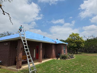 Worker on a ladder installing a metal roof.