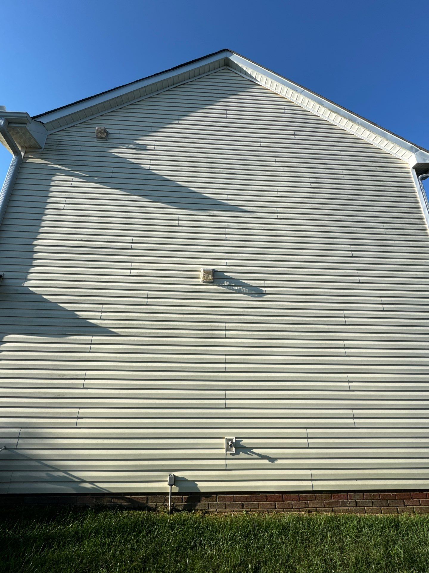 the service shown is cleaning the exterior vinyl siding of a house using pressure washing techniques