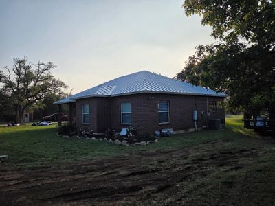 Completed metal roof on a brick home, clear view.