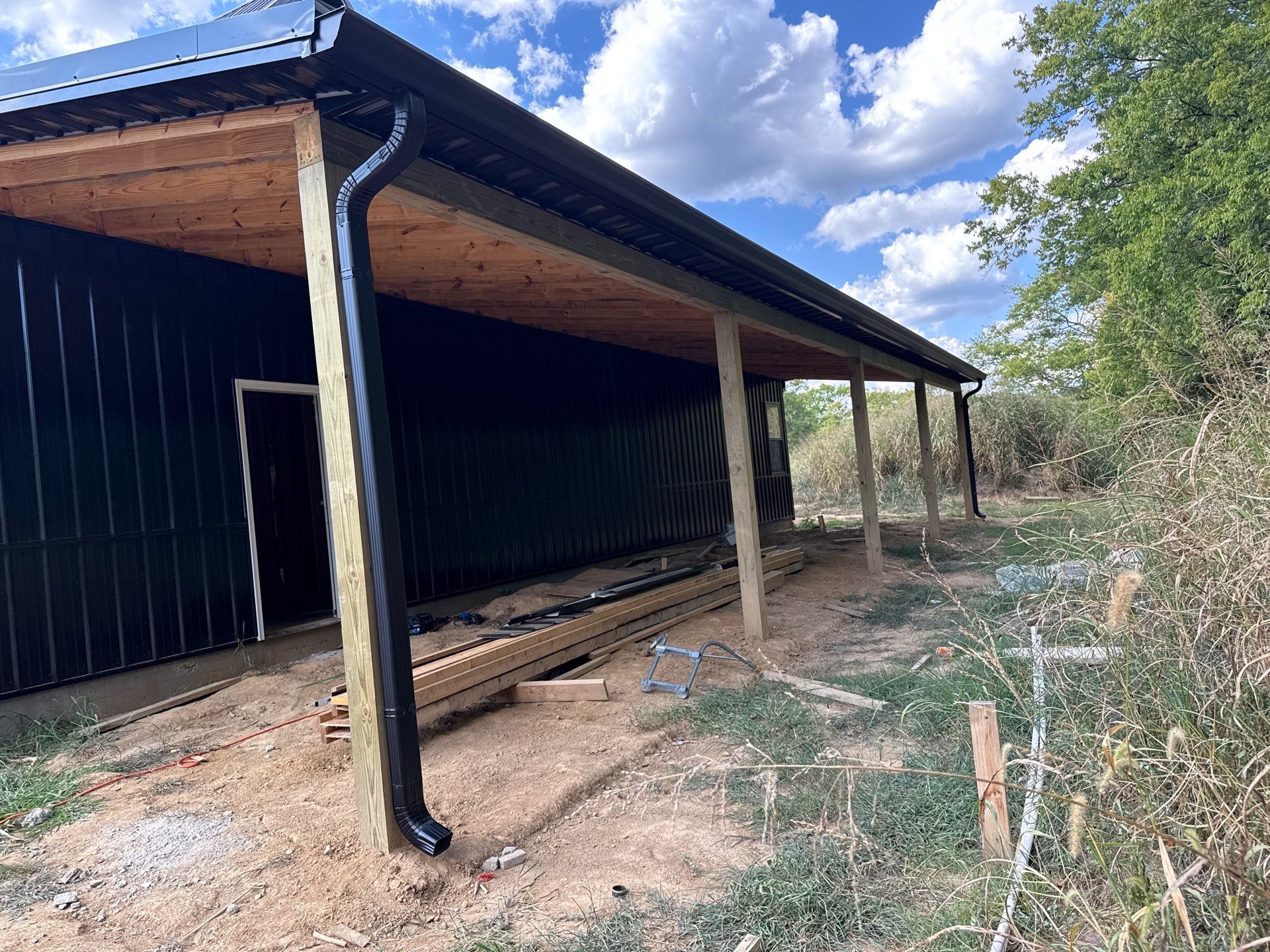 Black gutters on black building  by First Choice Gutters LLC
