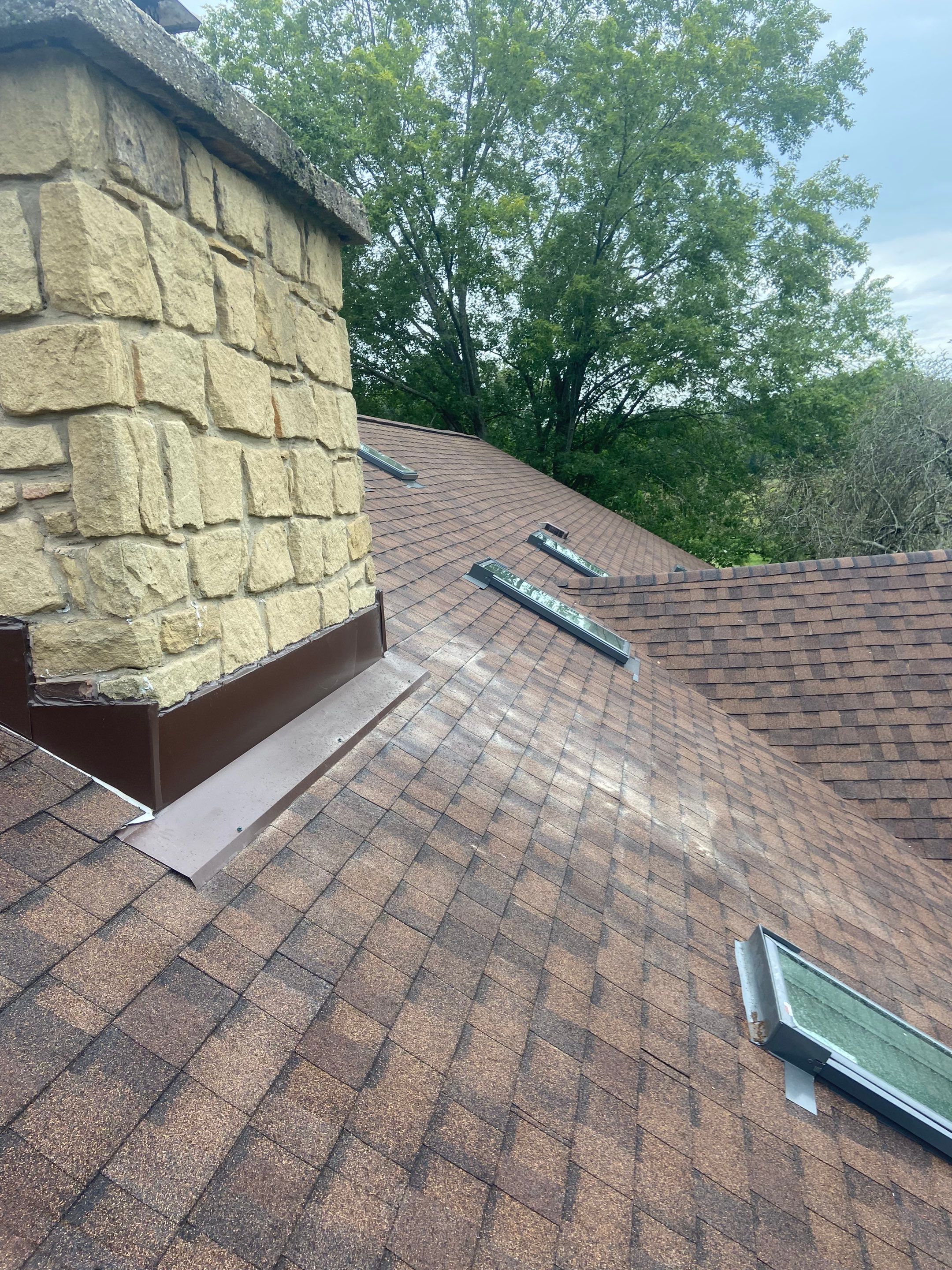 Shingle Roofing with Velux Skylight replacement and stone chimney flashing  by Secure Construction Company Inc