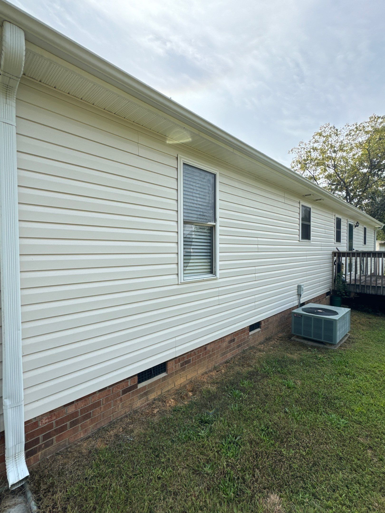 the service is cleaning the vinyl siding and brick foundation of a house using pressure washing techniques