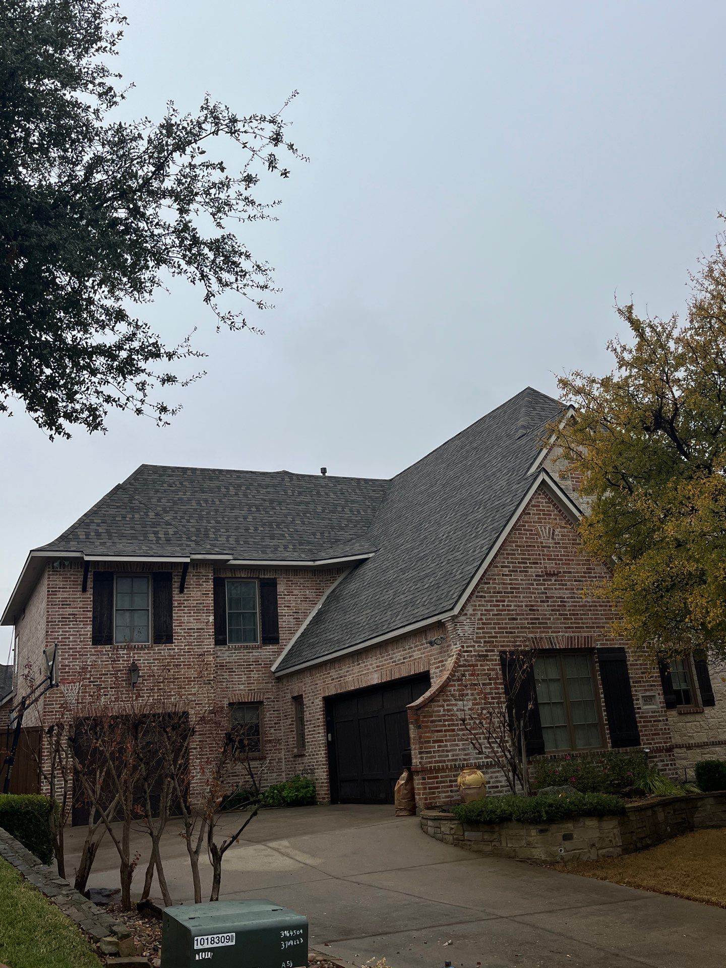 Light red brick/cream stone/espresso shutters with IKO Cornerstone by Tejas Roofworks + Restoration