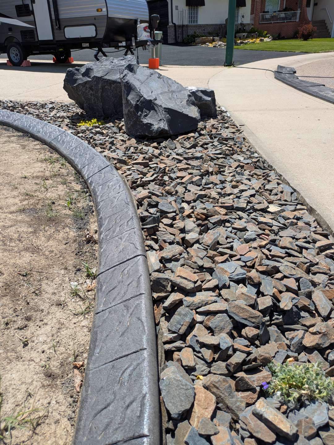 Custom Stamped Concrete Curbing and Decorative Rock Bed Installation by Pump it Up Concrete Jacking