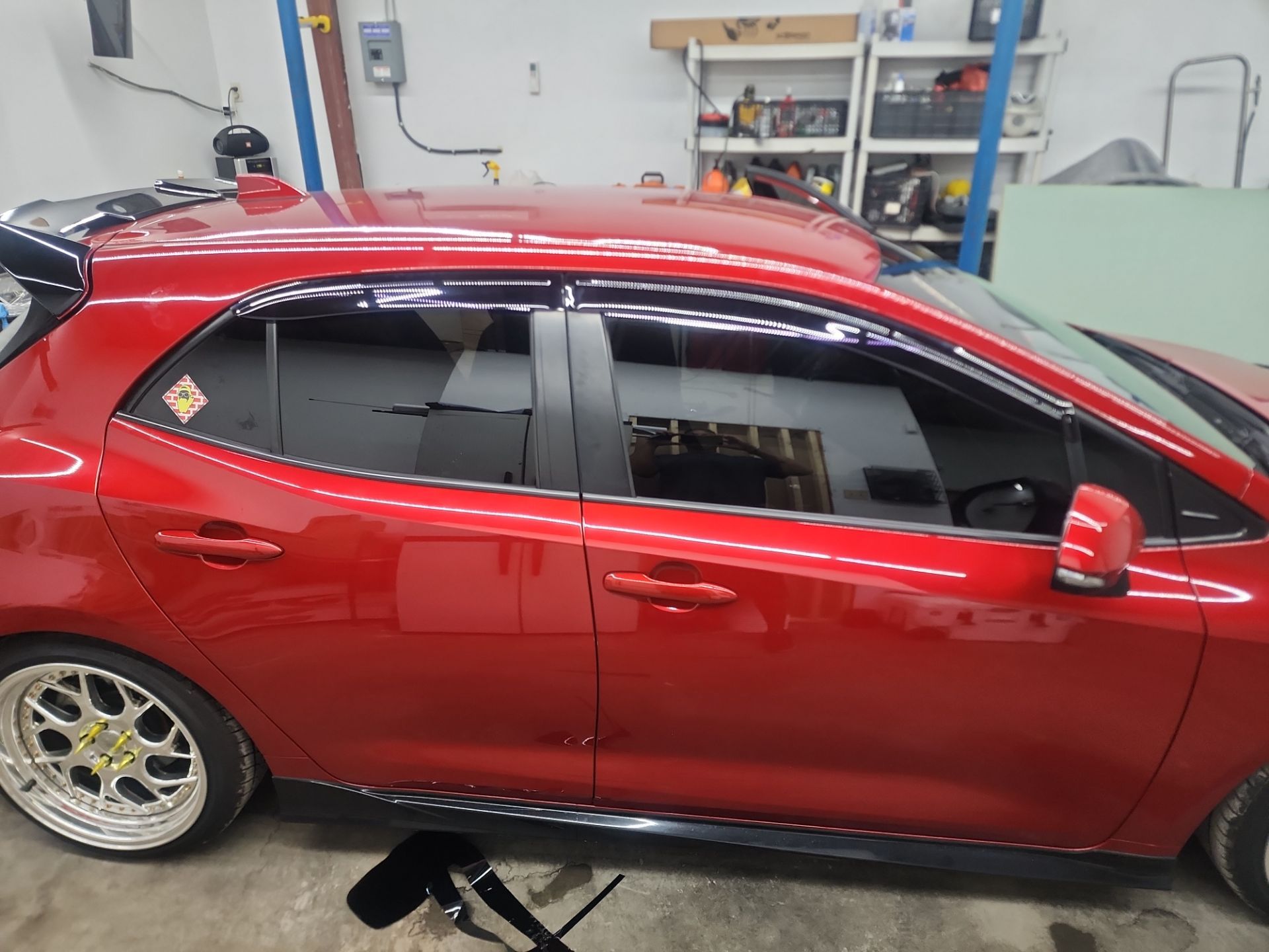 a bright red hatchback car is shown the windows have been freshly tinted to reduce glare and improve privacy there appears to be a high quality tinting film applied to all side windows of the vehicle the work looks precise and professionally done reflecting the expertise of t's window tinting in pensacola fl