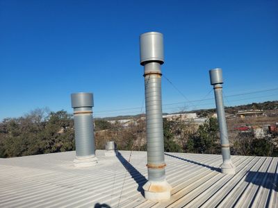 Metal roof with multiple vertical ventilation pipes.