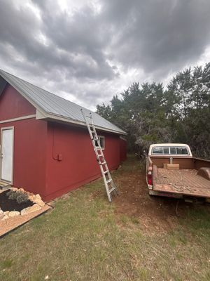 Completed metal roof on a red building with ladder
