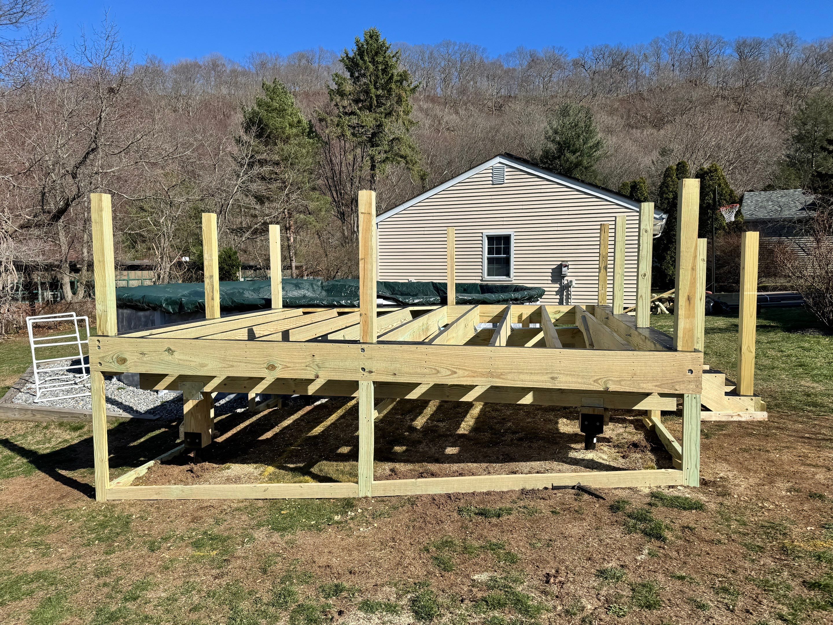 New pool deck using Trex Pebble Gray boards and White composite railings and lattice  by DiGiorgi Roofing and Siding Inc