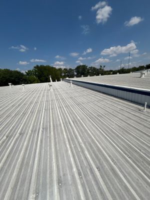 Completed corrugated metal roof with vents and blue sky