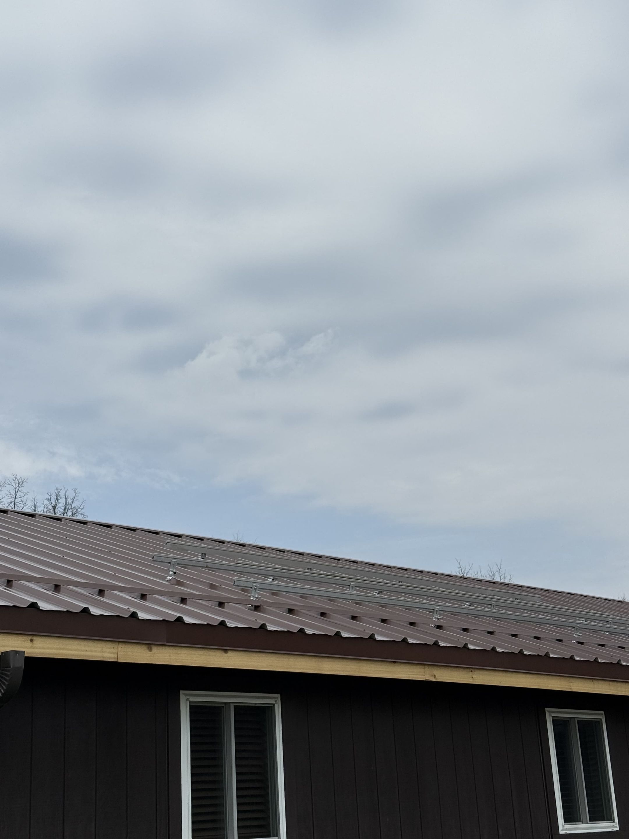 Brown R-Panel metal roof with solar by Atlas Roofing & Restoration