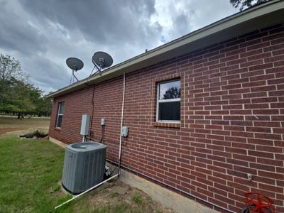 Exterior view of a red brick home with satellite dishes.
