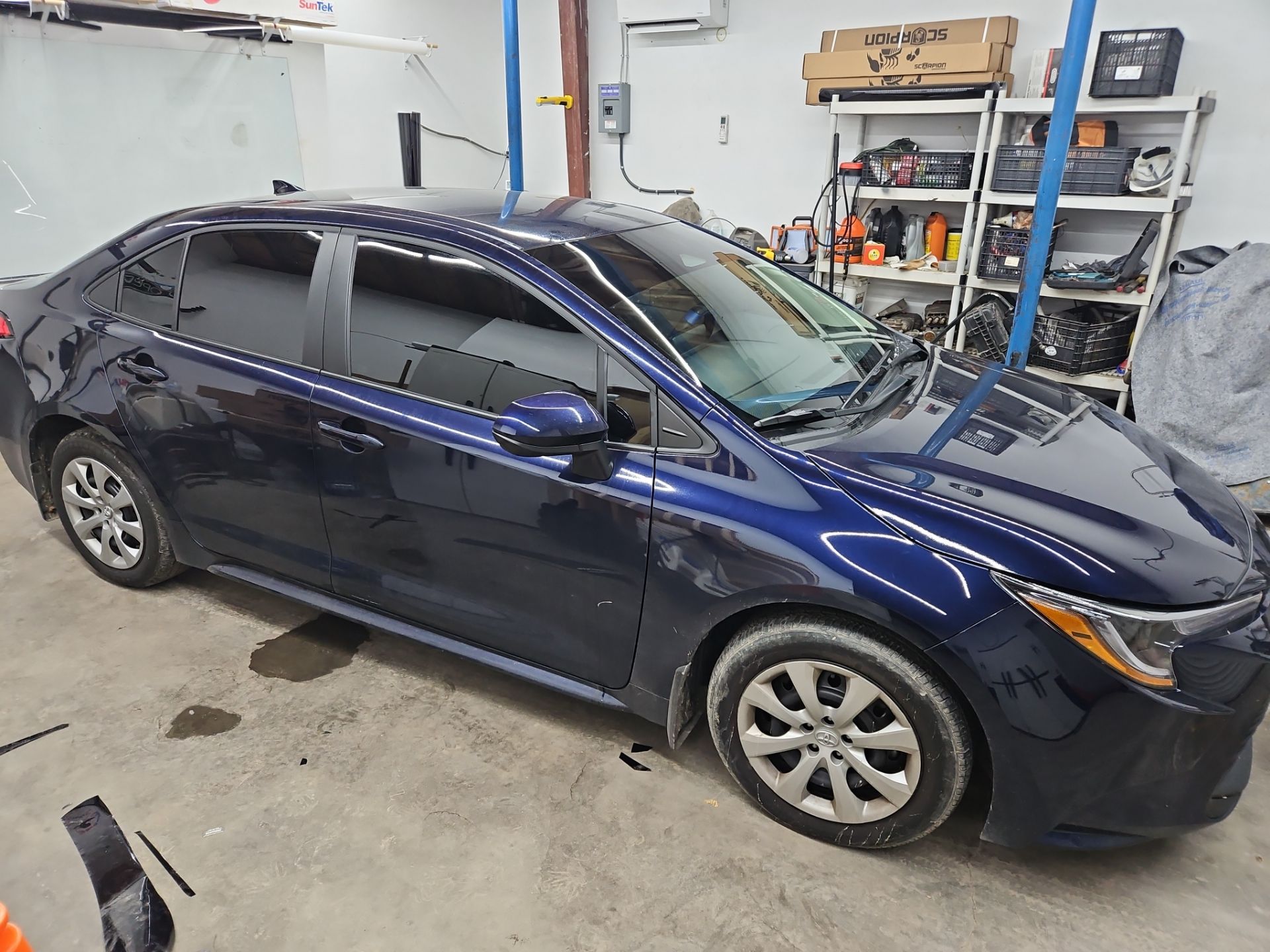 the service being performed is window tinting on a dark blue sedan the windows have been tinted with a dark film providing privacy and heat reduction the car appears to be in a clean and organized setting typical of a professional tinting shop the attention to detail suggests a thorough installation process ensuring high quality results the vehicle is likely being prepped for final inspection after the tint has been applied