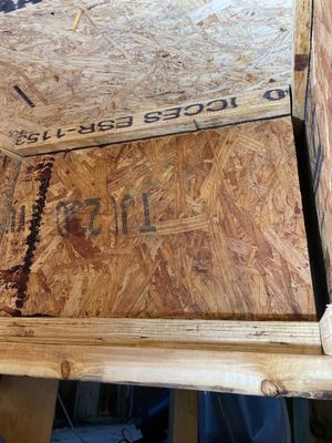Close-up of wood sheathing panels with visible staining along an edge near framing.