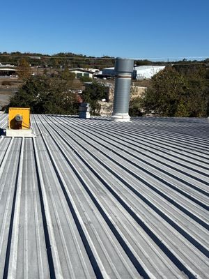 Metal roof with large vent pipe and yellow equipment