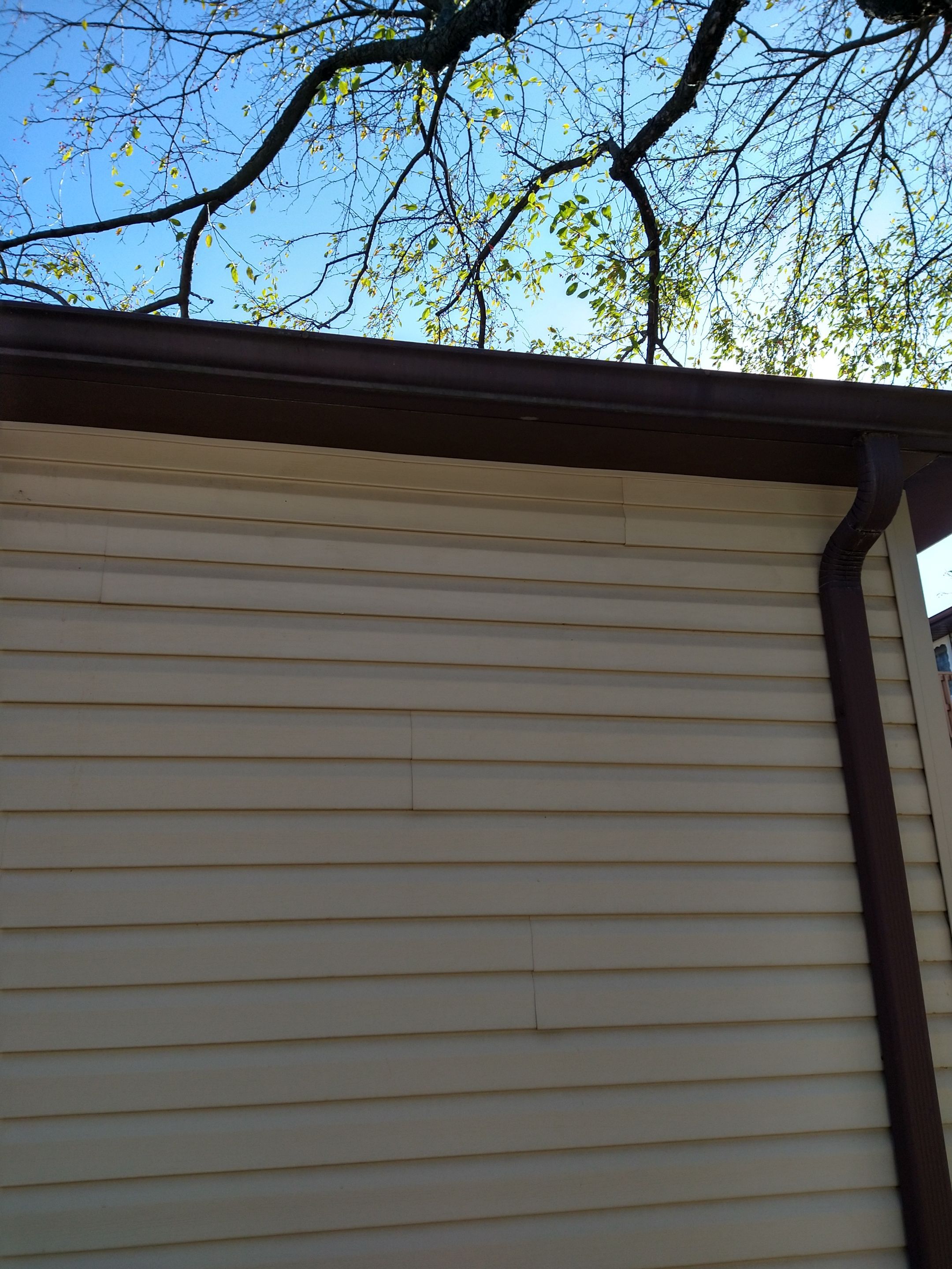 Siding Installation using Norandex woodsman dl-5 white woodgrain vinyl by Absolute Roofing and Construction