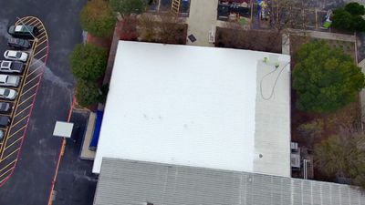 Aerial view of white flat roof and adjacent building section