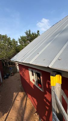 Metal roof on red building with ladder in foreground