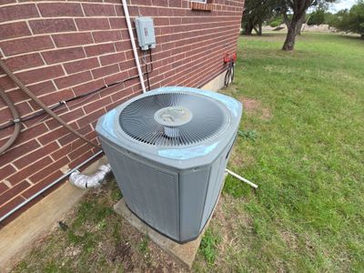 Wide view of HVAC unit next to brick wall