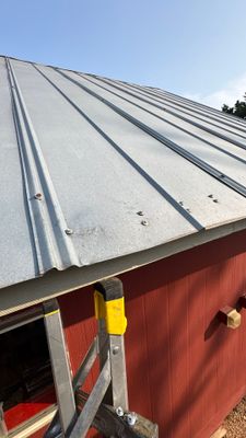 Metal roof panels on red building with ladder