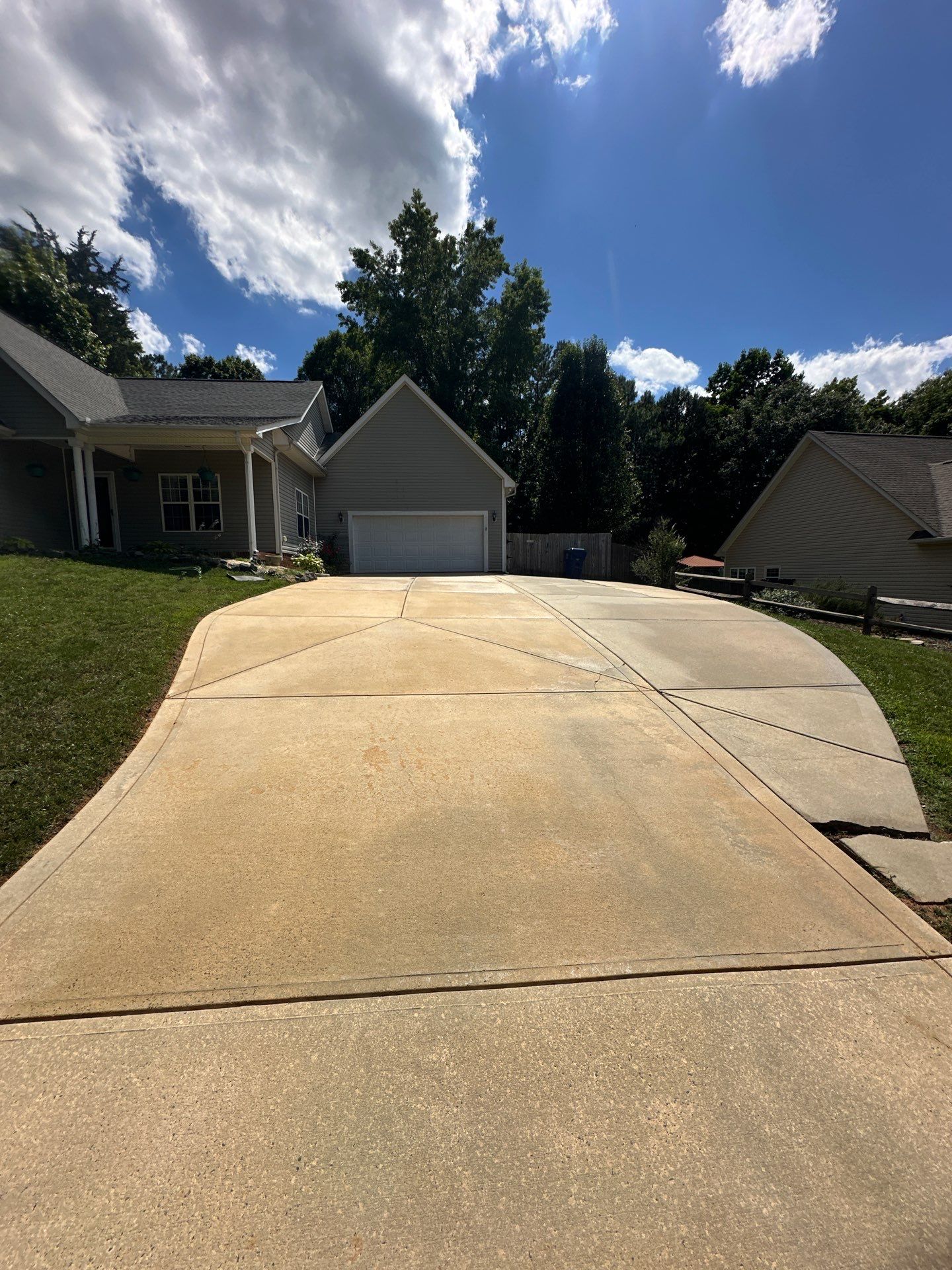 the service shown in the photo is pressure washing or power cleaning of a concrete driveway leading up to a residential garage the image shows a clear contrast between the cleaned portion of the driveway and the yet-to-be-cleaned section it indicates effective removal of dirt grime or possibly mildew to restore the surface to a cleaner and more aesthetically pleasing state