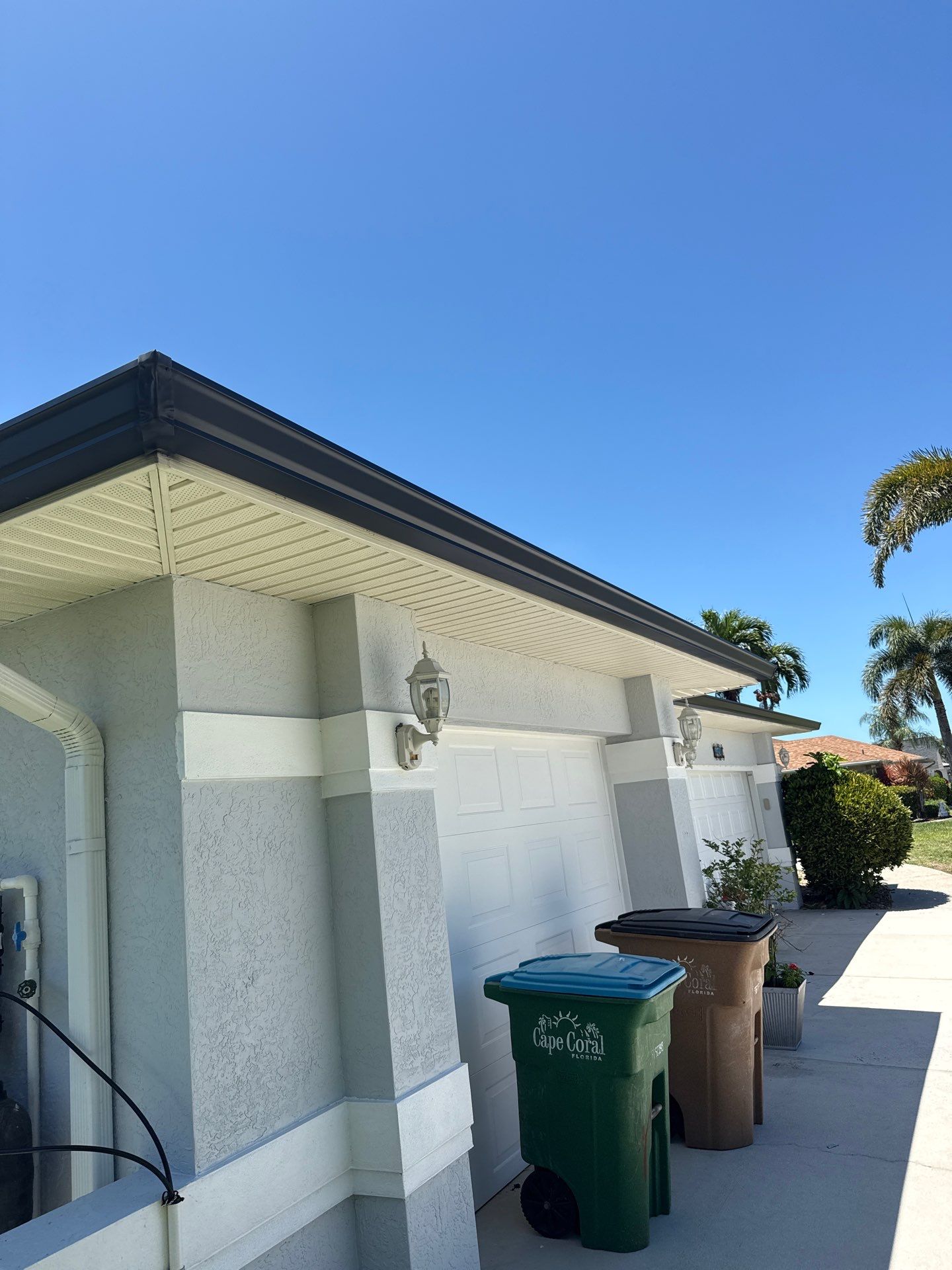 Black Seamless Gutters and White Downspouts in Cape Coral FL by Gutter Professors