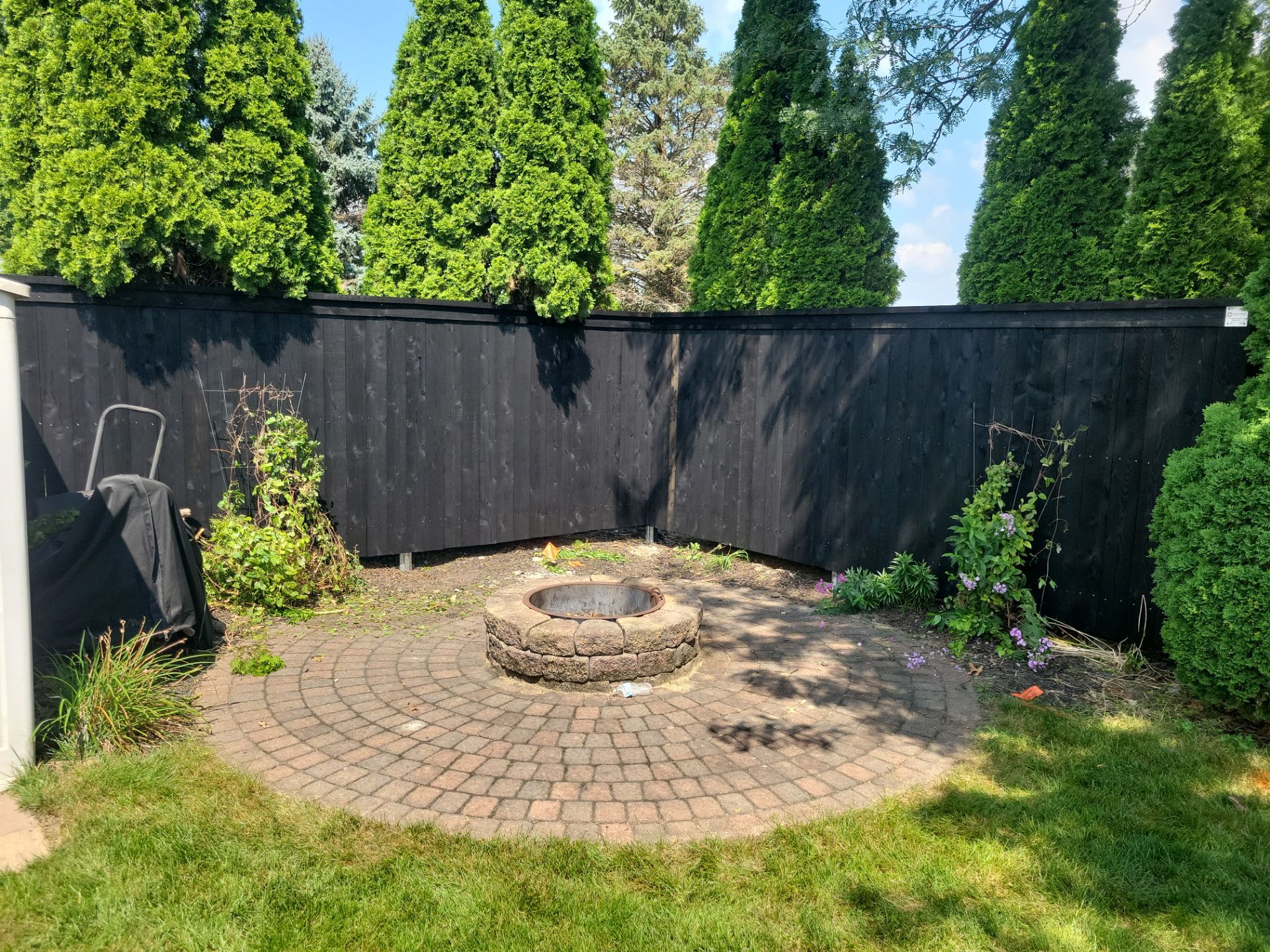 Black Wood Privacy Fence and Circular Stone Patio in Waverly by Perfect Picket Fence and Stain