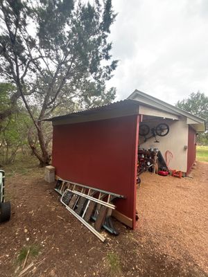 Side view of red building with metal roof and ladders