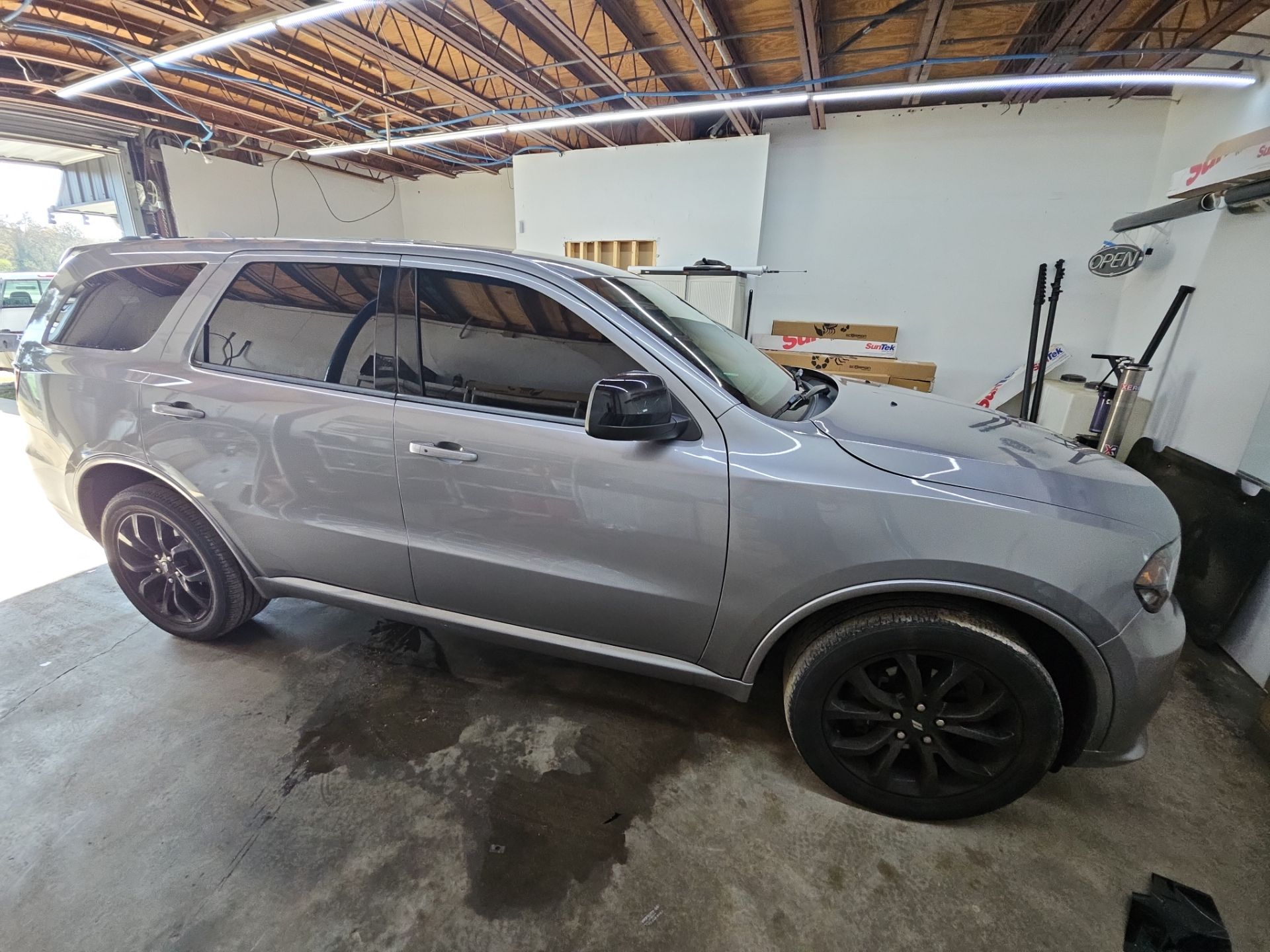 the service being done in the photo is window tinting on a silver suv the vehicle has been parked inside a workshop where t's window tinting operates the windows appear to be clean and ready for the application of tinted film this process will help reduce heat and glare while enhancing privacy and aesthetics of the vehicle the suv has black alloy wheels adding to its overall look