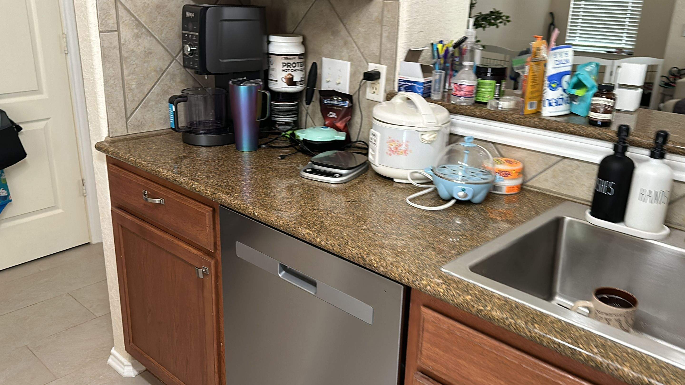 The old kitchen had a traditional builder-grade look with heavier wood cabinetry and busier finishes, while the new kitchen has a warm transitional design with cleaner lines, a brighter palette, and a more open, modern layout by Mena stone surfaces