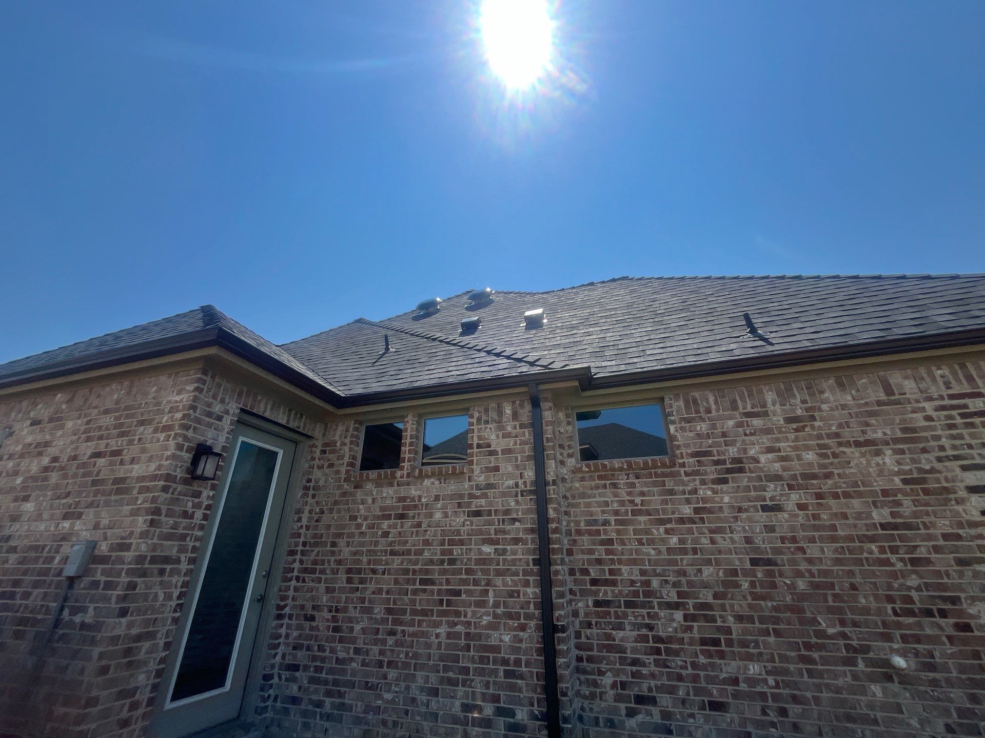 IKO Granite Black-Light Brown with dark brown sections brick house  by Tejas Roofworks + Restoration