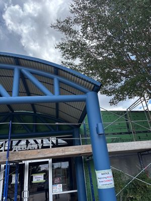 Curved metal roof entryway with blue steel supports.