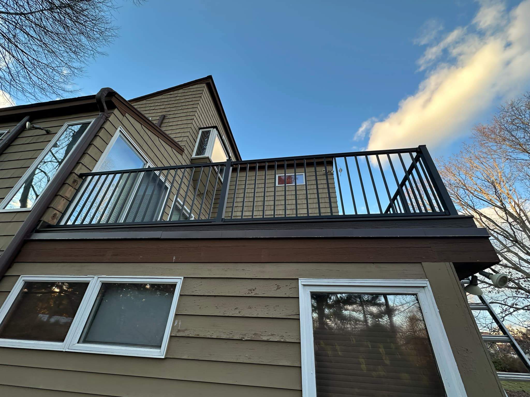 Replacement deck on top of flat roof, Trex Tropical Spiced rum boards and fascia, Trex signature aluminum railings in Black. by DiGiorgi Roofing and Siding Inc