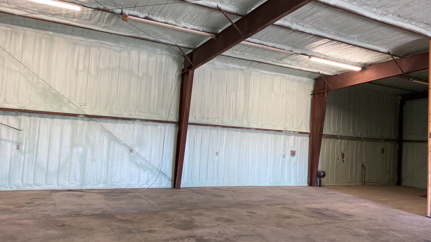 Spray foam insulation on inside of metal industrial building by Straight Edge Roofing Inc