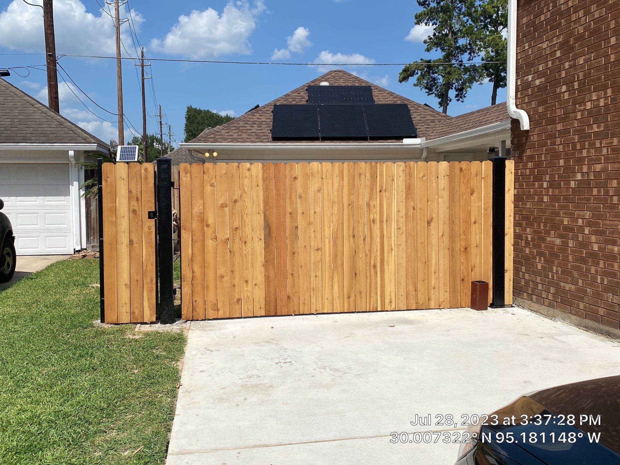 Complete metal driveway gate install with solar powered opener. Metal fence frame with Cedar Pickets by Astro Outdoor Designs 