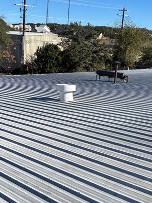 Metal roof with white vent pipe on commercial building