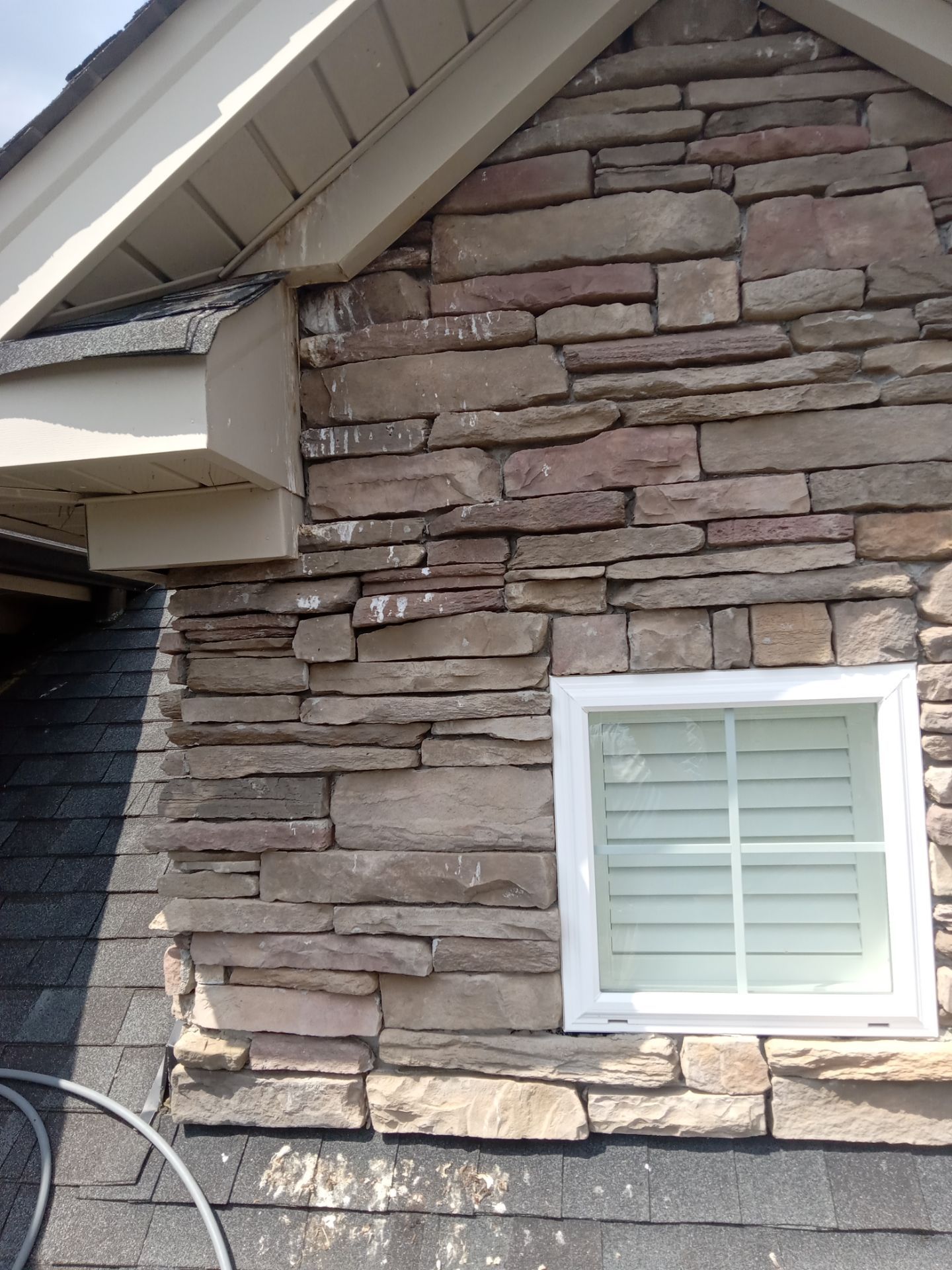 pressure washing exterior stone wall and siding removing dirt buildup and stains to restore appearance