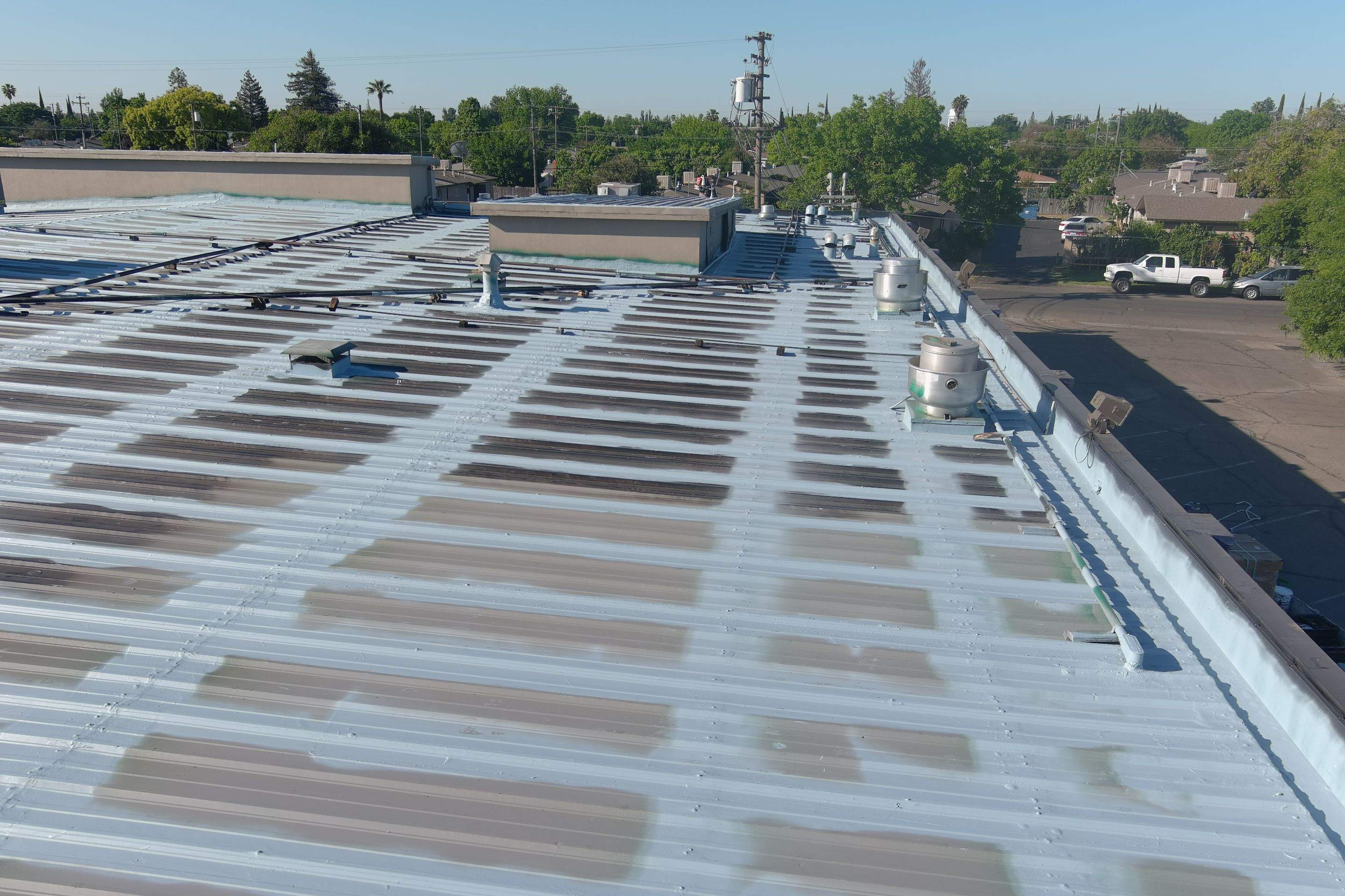 Metal roof restoration on commercial roof using Conklin Benchmark/ PUMA XL acrylic coatings over metal and foam by Straight Edge Roofing Inc