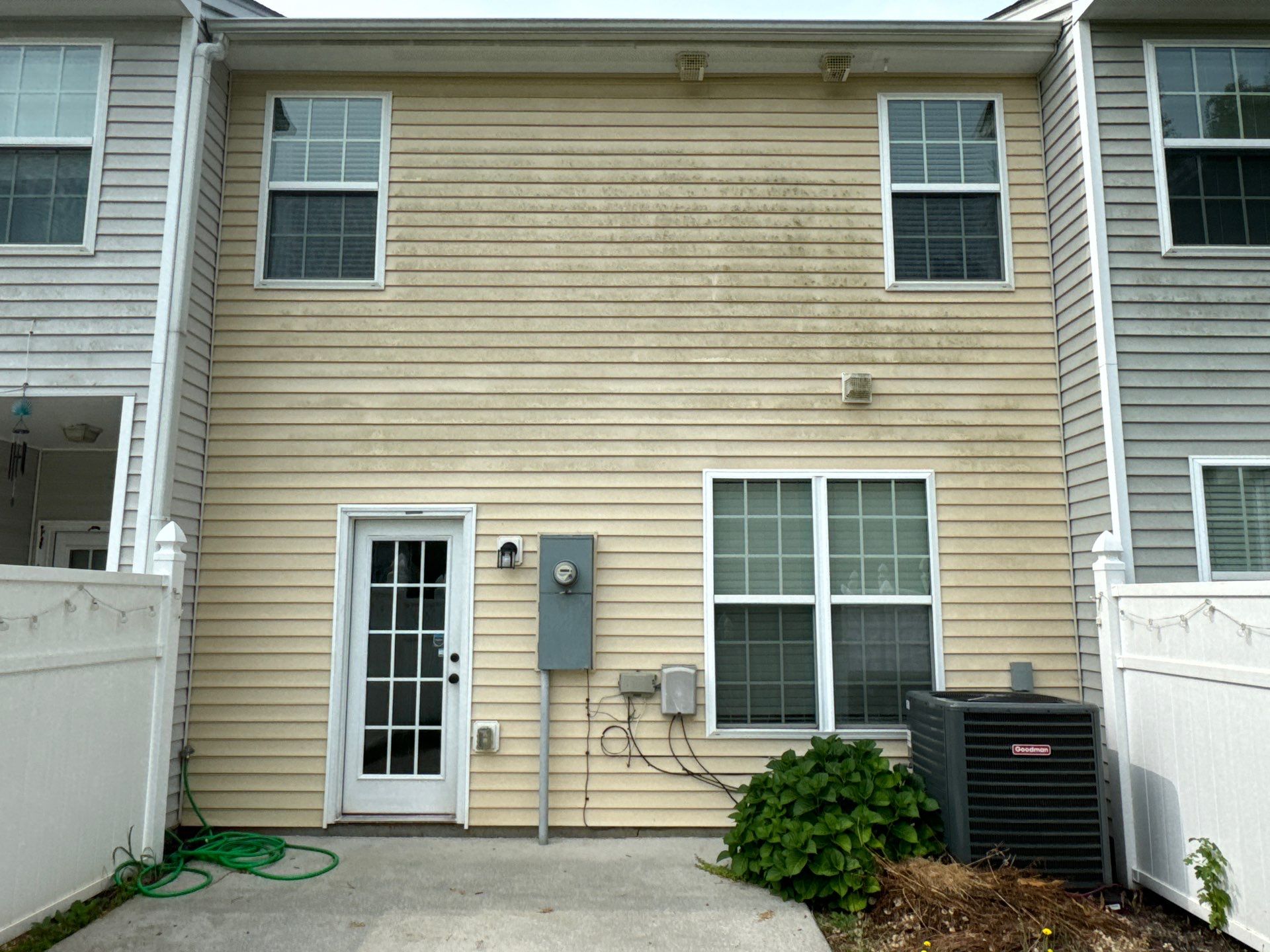 pressure washing exterior siding of a house to remove dirt and mildew