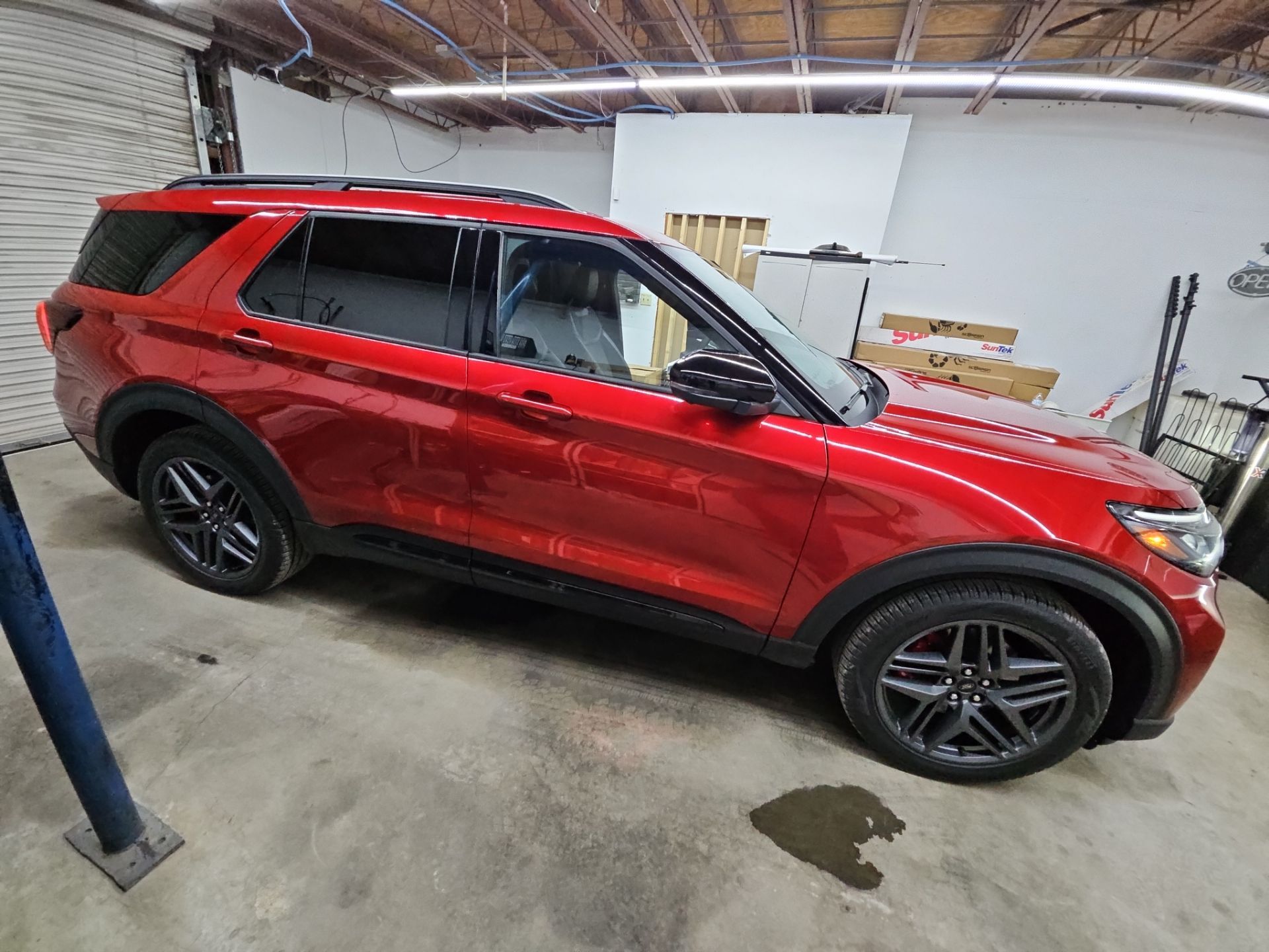 the image shows a red suv receiving window tinting service the windows are partially tinted which will enhance privacy reduce glare and improve aesthetics the vehicle appears clean and ready for the tint application the service aims to provide a sleek look while also offering protection from harmful uv rays and heat the work is being done in a clean and professional environment