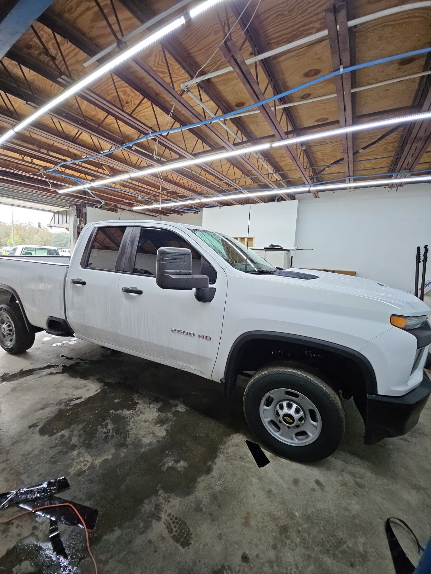 the image shows a white truck being prepped for window tinting the truck is likely being cleaned to ensure a proper bond for the tint film the surface appears to be wet indicating that cleaning is in progress this process is essential to remove any dirt and debris before the tint is applied the truck has a simple design and is likely a work vehicle the overall scene suggests a professional environment focused on quality window tint installation