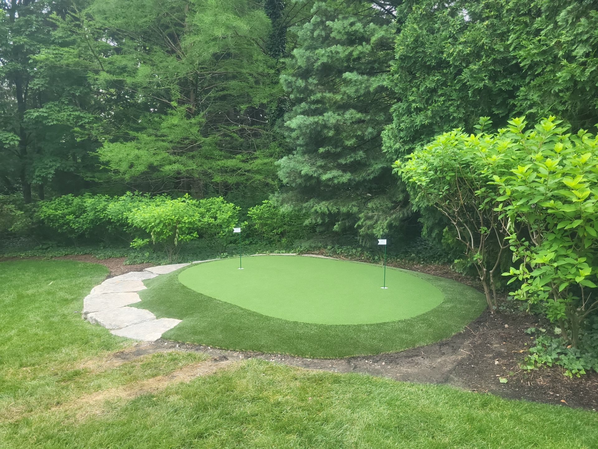 Small New Albany Synthetic Turf Putting Green with Natural Stone Border by Southwest Greens Midwest