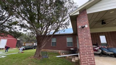 Workers installing a new metal roof on a brick home.