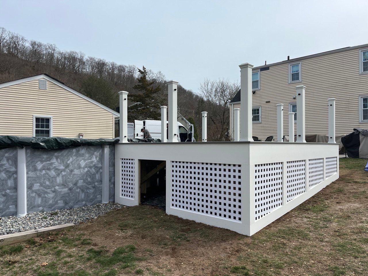 New pool deck using Trex Pebble Gray boards and White composite railings and lattice  by DiGiorgi Roofing and Siding Inc