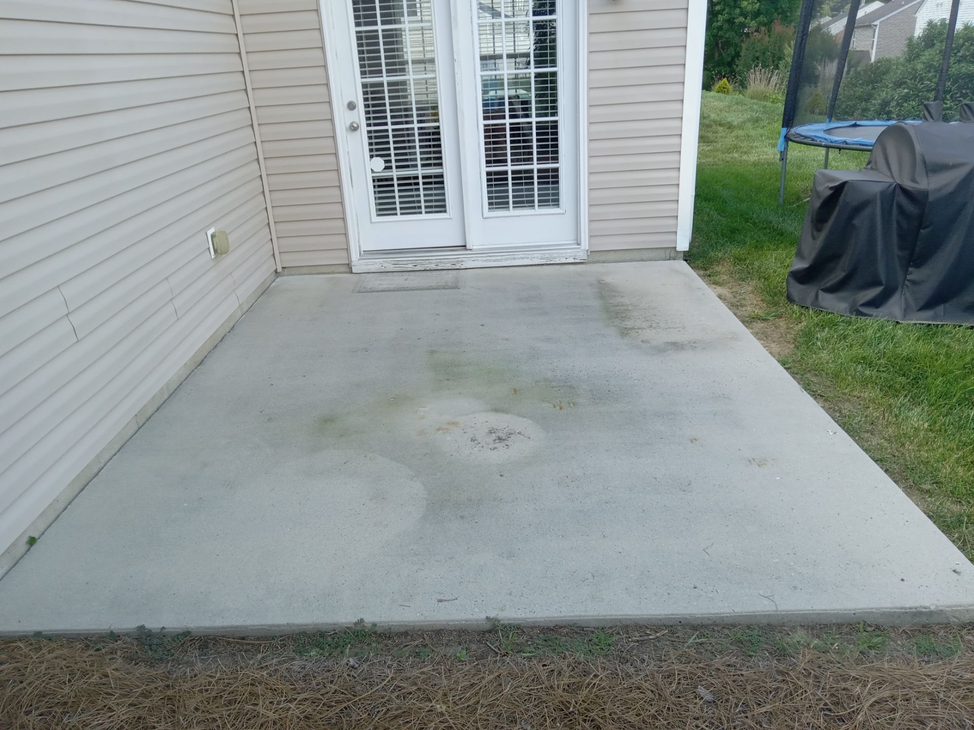 the image shows a concrete patio with visible dirt and discoloration pressure washing services would typically clean the patio by using high-pressure water to remove the grime mildew and any stains from the surface restoring the concrete's appearance they might also treat the surface with cleaning solutions if necessary for tougher stains or algae growth the company may clean similar surfaces such as sidewalks driveways and other concrete or hard surfaces around the property