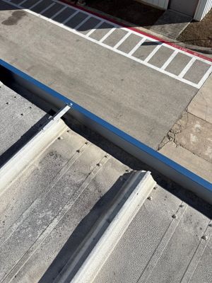 Metal roof edge detail overlooking a parking lot
