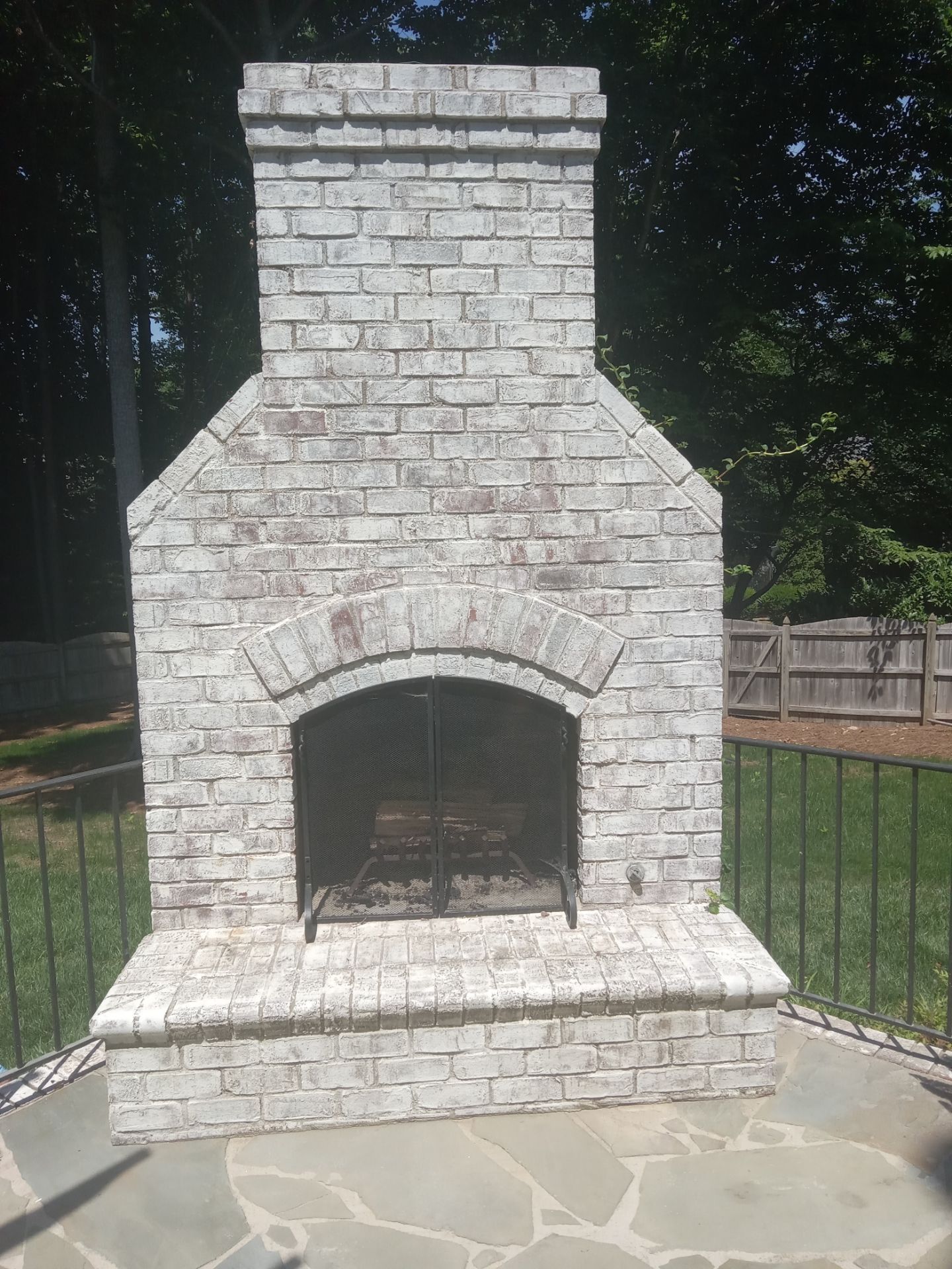 pressure washing stone outdoor fireplace and surrounding flagstone patio area