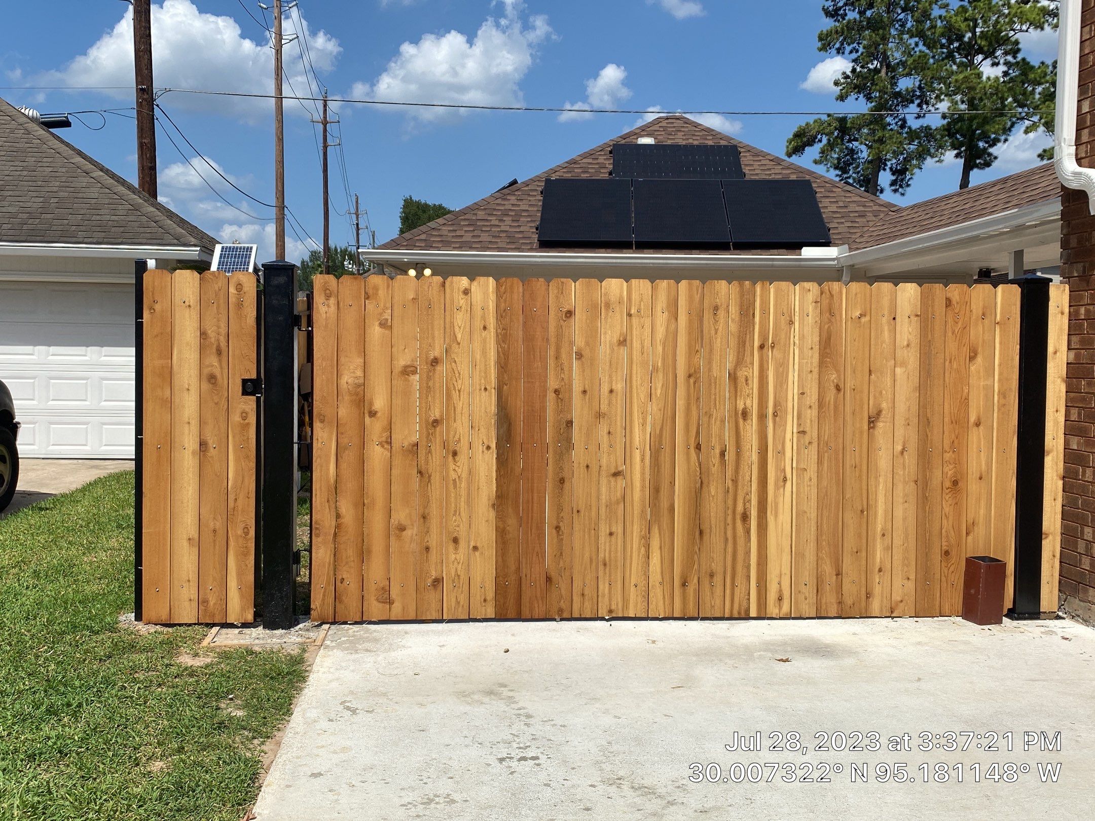 Complete metal driveway gate install with solar powered opener. Metal fence frame with Cedar Pickets by Astro Outdoor Designs 