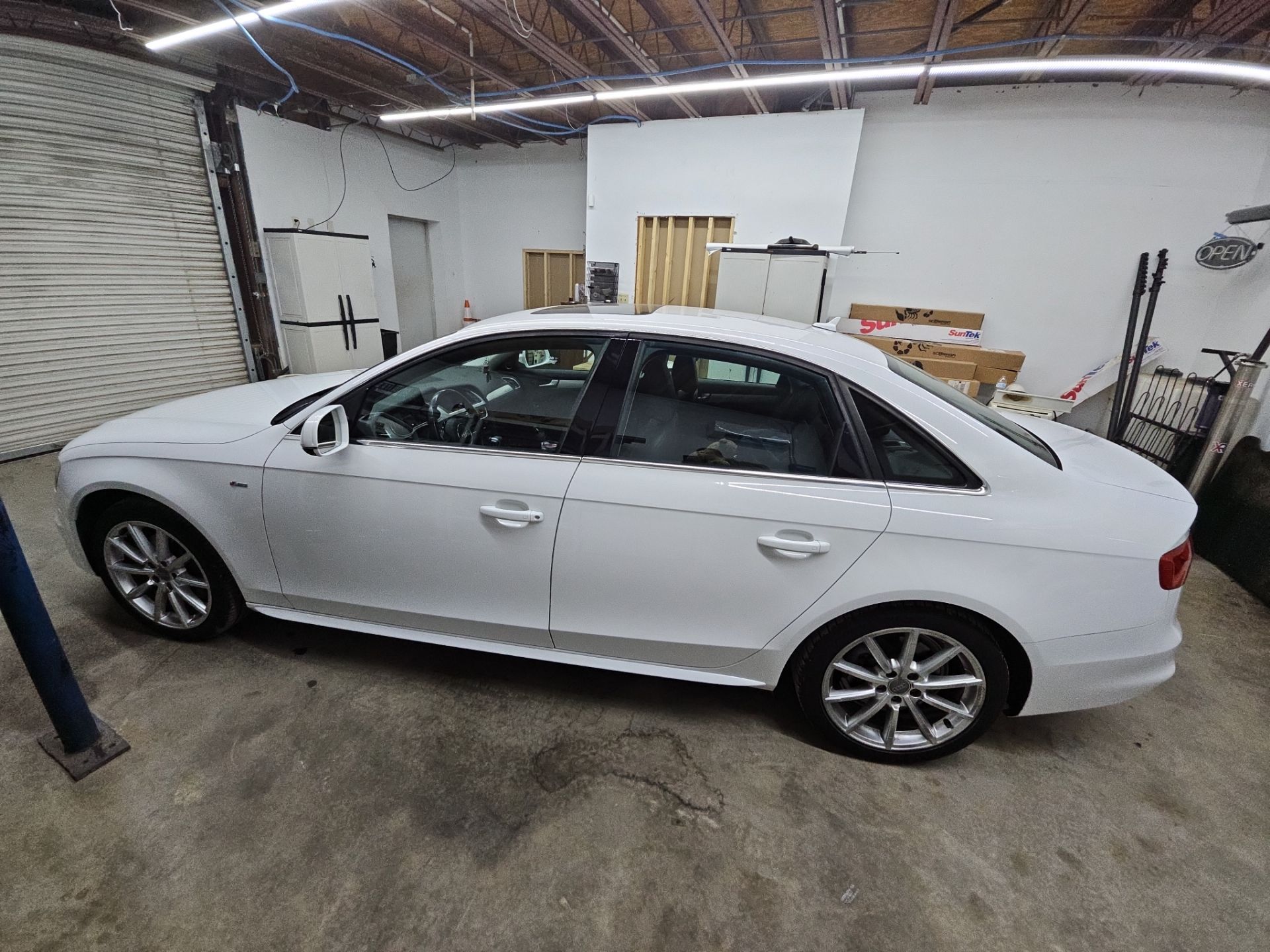 the image shows a white sedan undergoing window tinting service by t's window tinting in pensacola the car is parked in a garage environment with clear visibility of the windows that are being prepared for tint application the process likely involves cleaning the glass thoroughly to ensure the tint adheres properly and achieves a smooth finish the vehicle appears to be a modern model which would benefit from enhanced privacy and UV protection provided by the tinted windows