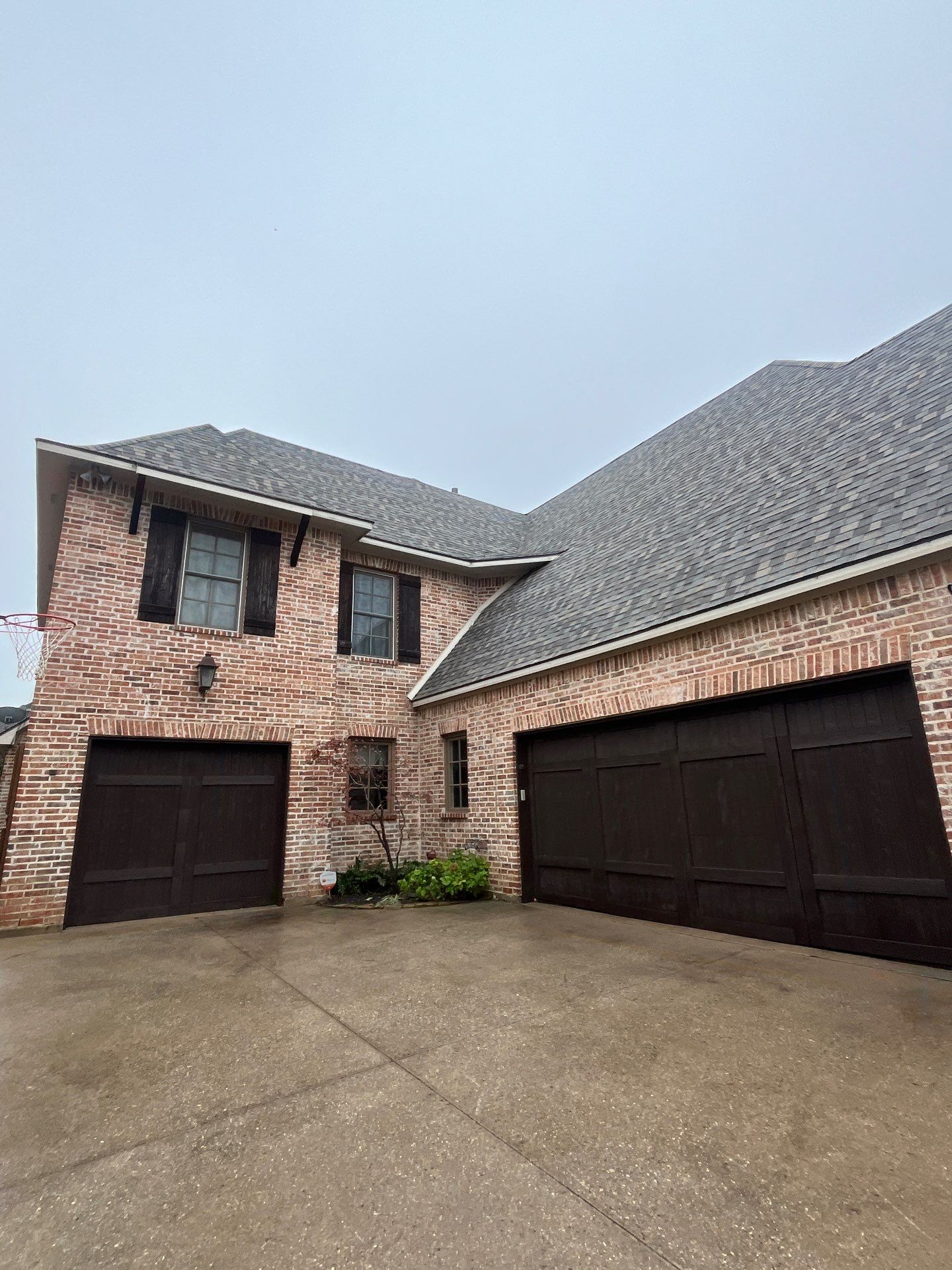 Light red brick/cream stone/espresso shutters with IKO Cornerstone by Tejas Roofworks + Restoration