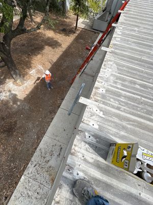 Worker on ground near metal roof and ladder